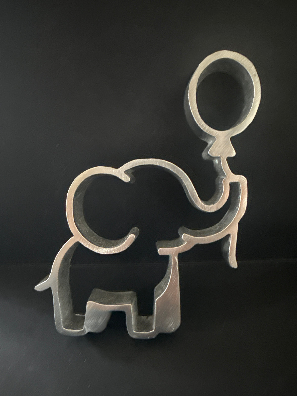Aluminum elephant-shaped rosette iron mold with raised trunk holding a balloon, used to make traditional Mexican buñuelos de viento for baby showers.